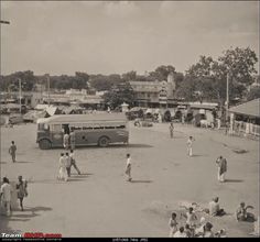 an old black and white photo of people playing in the street with a bus parked nearby