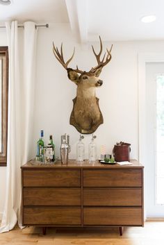 a deer head mounted on the wall above a dresser