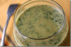 a glass filled with green liquid sitting on top of a table next to a fork