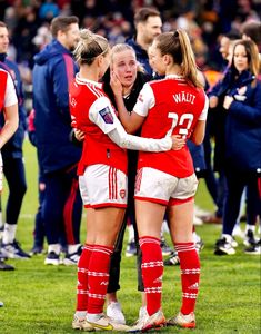 two female soccer players hugging each other on the field