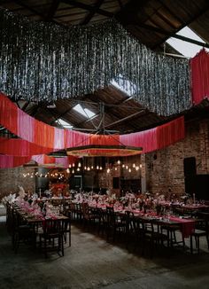 a large room with tables and chairs covered in pink tablecloths hanging from the ceiling