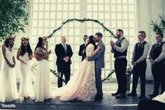 a group of people standing next to each other in front of a wedding ceremony arch