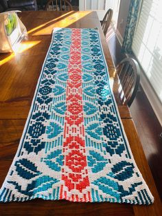 a table runner made out of knitted fabric on top of a wooden dining room table