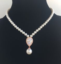 Classic clear cubic zirconia teardrop and pearls bridal necklace in rose gold plated brass setting. This gorgeous necklace features a large teardrop pendant with pear cut clear cubic zirconia center surrounded by tiny round zirconia crystals with a dangling 12mm swarovski pearl drop. This pendant is strung in a row of 6mm Swarovski pearls. Length of the necklace is 16 inches and comes with 2 inches adjustable extender and lobster clasp. Necklace is also available with a 7 inch matching backdrop Rose Gold Teardrop Necklace With Pearl Pendant, Rose Gold Pearl Drop Necklace For Wedding, Rose Gold Teardrop Drop Necklace For Wedding, Wedding Rose Gold Teardrop Drop Necklace, Rose Gold Pear-shaped Necklace For Wedding, Wedding Drop Necklace With Pearl Charm And Teardrop Pendant, Teardrop Pearl Pendant Necklace For Wedding, Pearl Pendant Teardrop Necklace For Wedding, Teardrop Pearl Necklace For Wedding