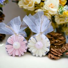 two flower shaped soaps sitting on top of a table next to pine cones and flowers