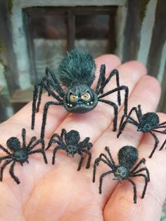 small black spider figurines sitting in the palm of someone's hand