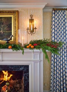 a mantel with candles and greenery in front of a painting on the wall