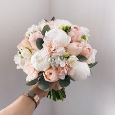 a bridal bouquet being held by a woman's hand with white and pink flowers