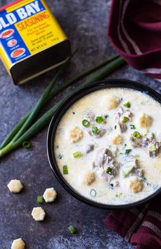 a bowl of soup with green onions and meatballs next to a carton of old bay seasoning