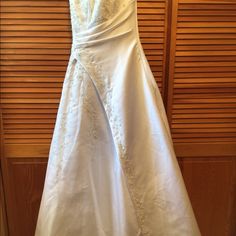 a white wedding dress hanging on a wooden door