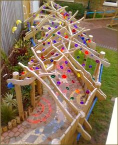 a wooden structure made out of sticks and colored glass beads is shown in the yard