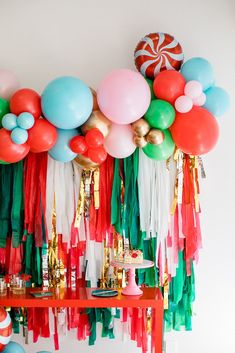 balloons and streamers are hanging on the wall above a table with cake, candies, and other decorations