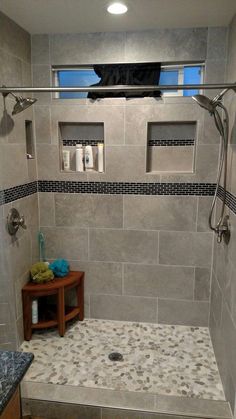 a walk in shower sitting next to a wooden table and tiled walls with windows above it