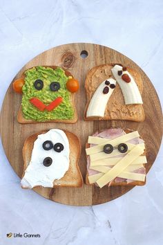 a wooden plate topped with sandwiches covered in fruit and vegtables, ghost face