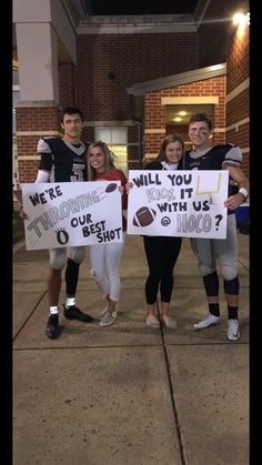 some people are holding signs and posing for a photo outside the building with footballs on them