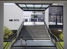 two people are walking down the stairs in front of a building with large windows on each side