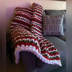 a crocheted blanket sitting on top of a couch next to a throw pillow