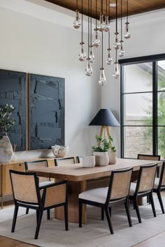 a dining room table with chairs and vases on top of it in front of a large window