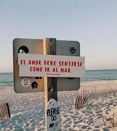 a sign that is on the side of a wooden pole in front of the beach