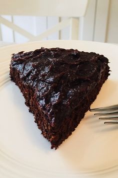 a piece of chocolate cake sitting on top of a white plate next to a fork