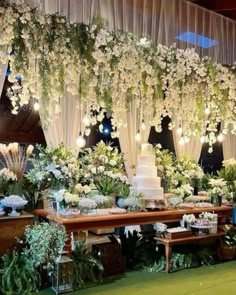 a table topped with lots of white flowers next to a wall covered in greenery