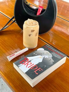 a table with a book, purse and drink on it