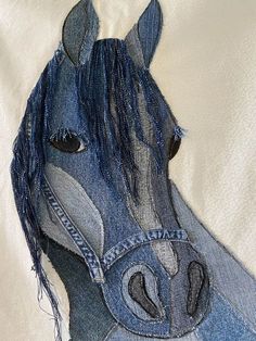 a horse made out of jeans on top of a white sheet covered in blue thread