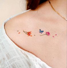 the back of a woman's shoulder with three small flowers and butterflies on it