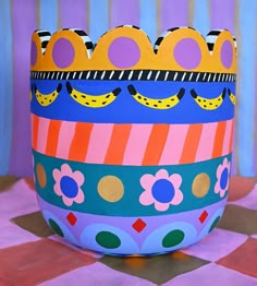 a brightly colored painted pot sitting on top of a checkered tablecloth covered floor