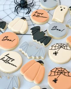 decorated halloween cookies on a table with spider webs and pumpkins in the background