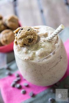 a glass with some food in it on top of a pink napkin and two bowls filled with cookies