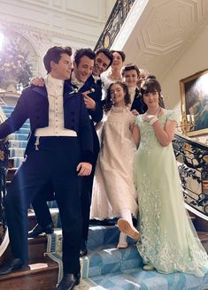 a group of people posing for a photo on the stairs in formal dress clothes and tuxedos