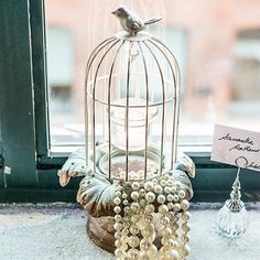 a birdcage filled with pearls sitting on top of a window sill next to a sign