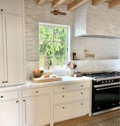 a kitchen with white cabinets and an oven in the center, along with a window that looks out onto trees