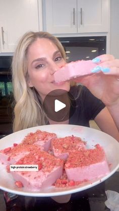 a woman is eating some food with pink frosting on her face and looking at the camera