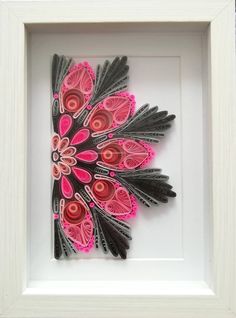 a white frame holding a pink and black paper art piece in it's center