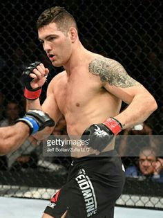 a man standing in front of a cage holding a boxing glove