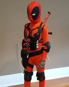 a man dressed in an orange and black deadpool costume with a baseball bat on his shoulder