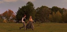 a man and woman walking across a lush green field