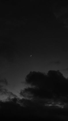 an airplane is flying in the sky at night, with dark clouds and moon behind it