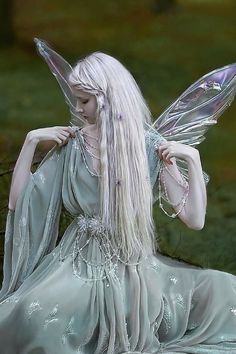 a white haired fairy sitting on the ground