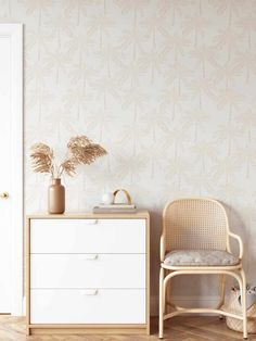 a white dresser sitting next to a chair in a room with a wallpapered background