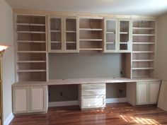 an empty room with white cabinets and wood floors