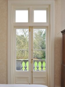 there is a bed and two doors in the room that lead to a balcony with trees outside