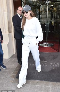 a woman in white is walking out of a building with her hands on her hips