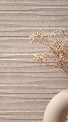 a vase with some flowers in it sitting on a table next to a striped wall