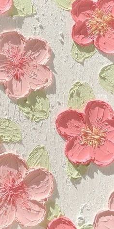 some pink flowers on a white surface with green leaves