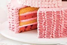 a cake with pink frosting on a plate next to a slice cut out of it