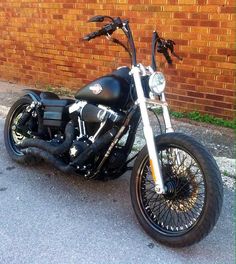 a black motorcycle parked next to a brick wall