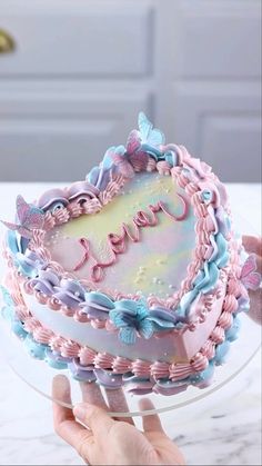 someone is holding a cake decorated with pink and blue icing